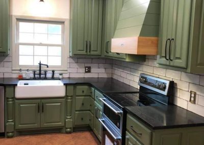 Kitchen with green cabinets and black countertops.