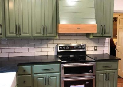 Kitchen with green cabinets and black countertops.