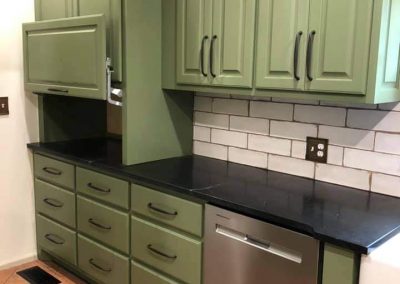 Kitchen with green cabinets and black countertops.
