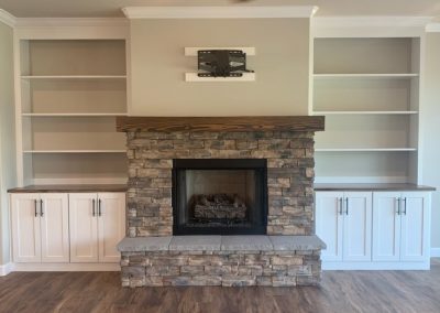 Fireplace surrounded by white cabinets and shelves.