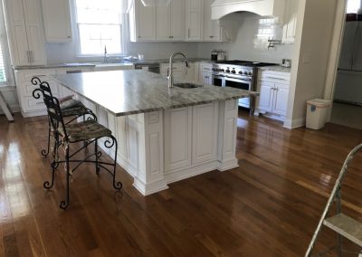 Beautiful kitchen with white cabinets, marble countertops, and hardwood floors.