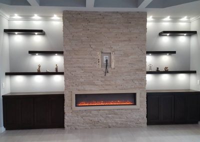 Fireplace surrounded by black cabinets and shelves.