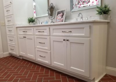 Twin bathroom sinks with white cabinets and drawers.