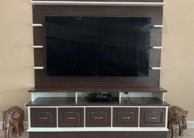 Whtie and brown entertainment center with cabinets and shelves, flanked by two miniature elephant statuettes.