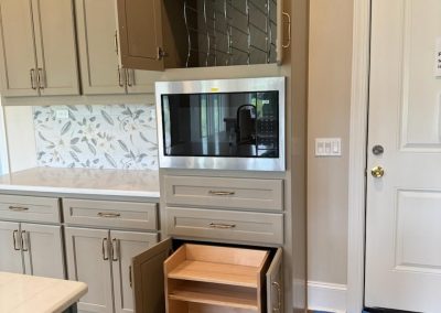 Gray kitchen cabinets with opened high-back tupperware drawer and dish organizers.